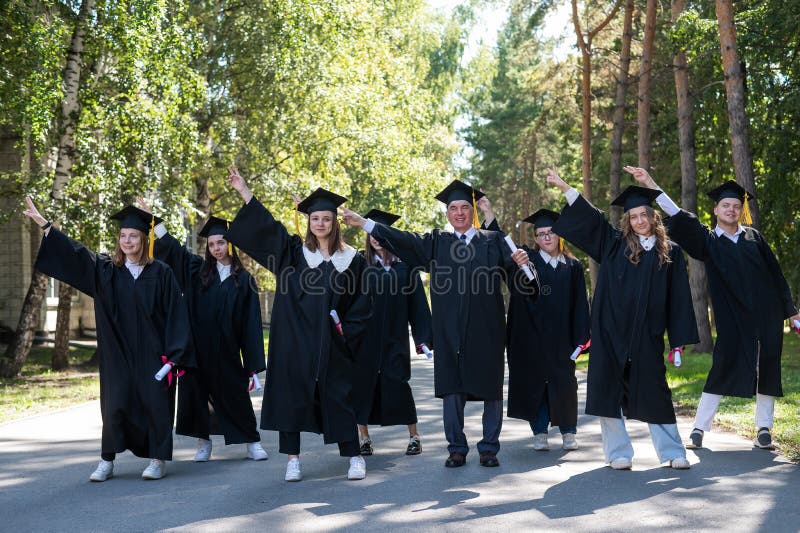 Group of graduates in robes dancing outdoors. Elderly student. Group of graduates in robes dancing outdoors. Elderly student