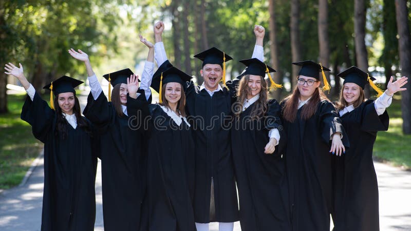 Group of happy graduates in robes outdoors. Group of happy graduates in robes outdoors