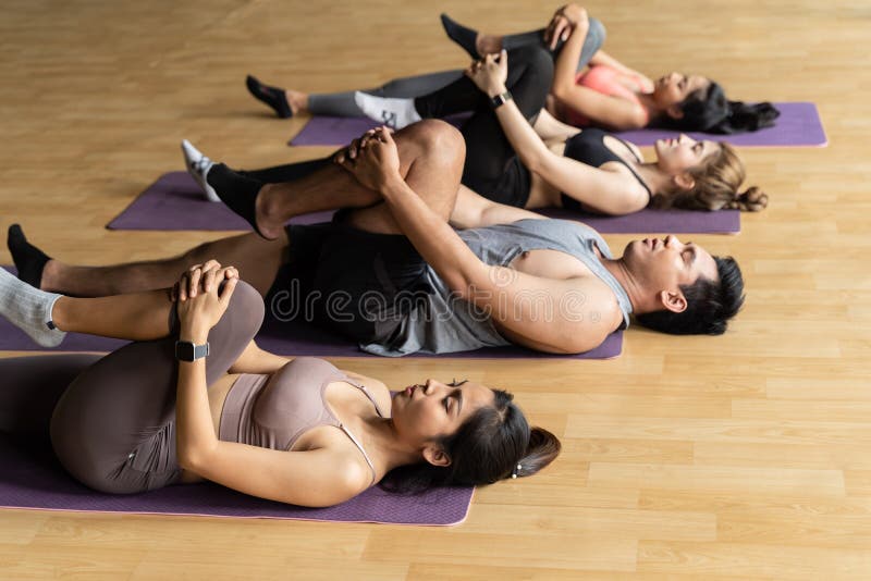 Foto de Grupo De Mulheres Asiáticas E Homens Fazendo Pilates Deitados Em  Tapetes De Yoga Na Aula De Aeróbica Jovens Esportivos De Joelhos Dobrados  No Chão E Colocar As Mãos Para Cima