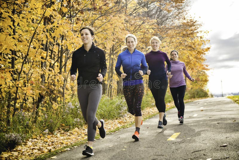 Grupo de mujeres corriendo juntas en un parque otoñal administran una carrera o un tren en un concepto de estilo de vida saludable foto de archivo libre de regalías