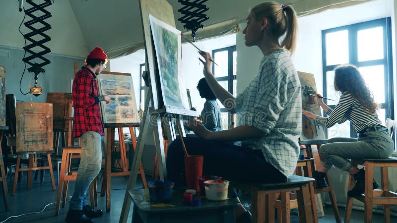 Grupo de mujeres están teniendo una clase de arte con un pintor masculino
