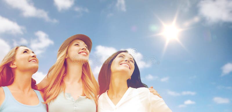 Grupo de mujeres o de amigos sonrientes felices sobre el cielo imagenes de archivo