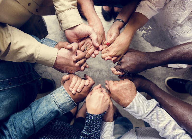 Grupo de mãos diversas que mantêm-se opinião aérea dos trabalhos de equipa do apoio unido