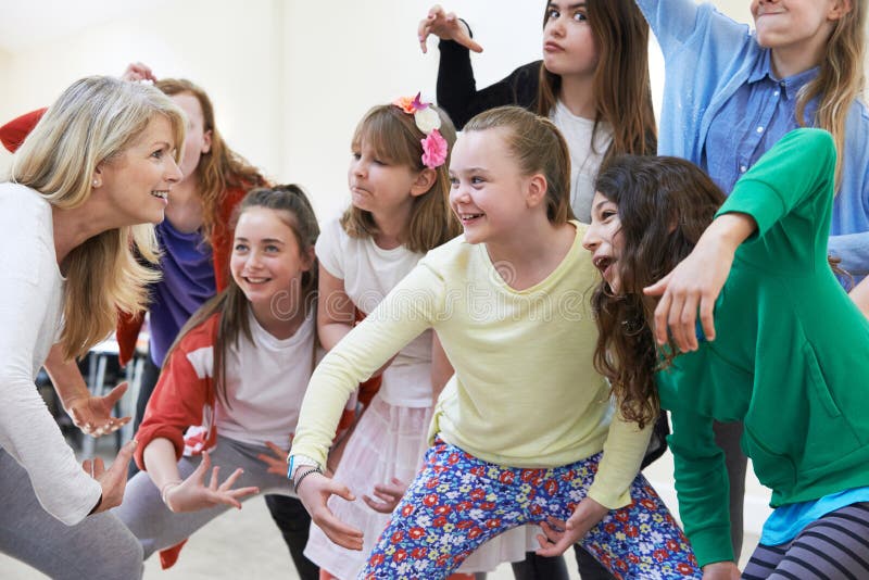 Un grupo de niños con su profesora disfrutando juntos de la clase de teatro foto de archivo