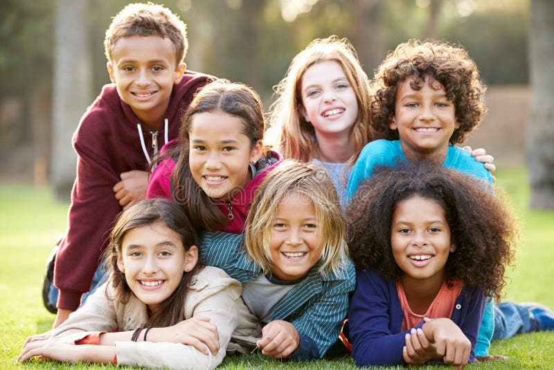 Grupo de niños que mienten en hierba junto en parque fotos de archivo Grupo de niños que mienten en hierba junto en parque fotos de archivo