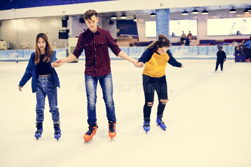 Grupo de patinagem no gelo adolescente dos amigos em uma pista de gelo imagens de stock Grupo de patinagem no gelo adolescente dos amigos em uma pista de gelo imagens de stock