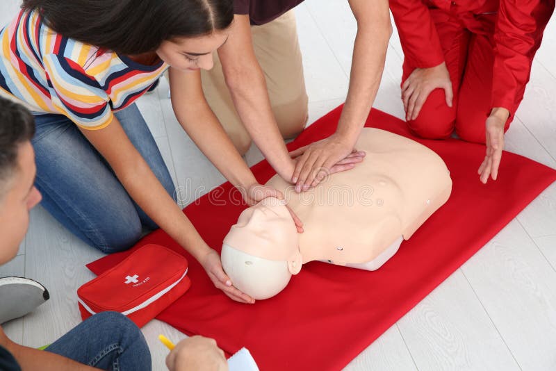Group of people with instructor practicing CPR on mannequin at first aid class indoors, closeup. Group of people with instructor practicing CPR on mannequin at first aid class indoors, closeup