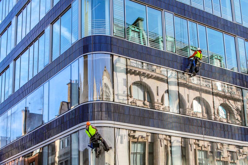 Grupo de trabajadores que limpian servicio de las ventanas en el alto edificio de la subida fotos de archivo Grupo de trabajadores que limpian servicio de las ventanas en el alto edificio de la subida fotos de archivo