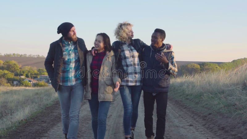 Grupo diverso feliz que camina en la trayectoria de la suciedad