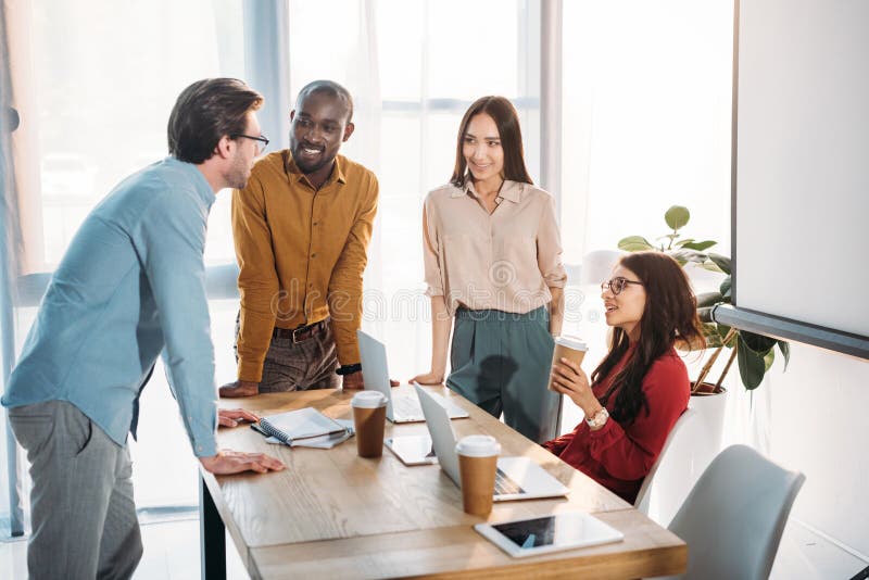 grupo inter-racial de colegas do negócio que discutem o trabalho durante a ruptura de café no local de trabalho fotografia de stock royalty free grupo inter-racial de colegas do negócio que discutem o trabalho durante a ruptura de café no local de trabalho fotografia de stock royalty free