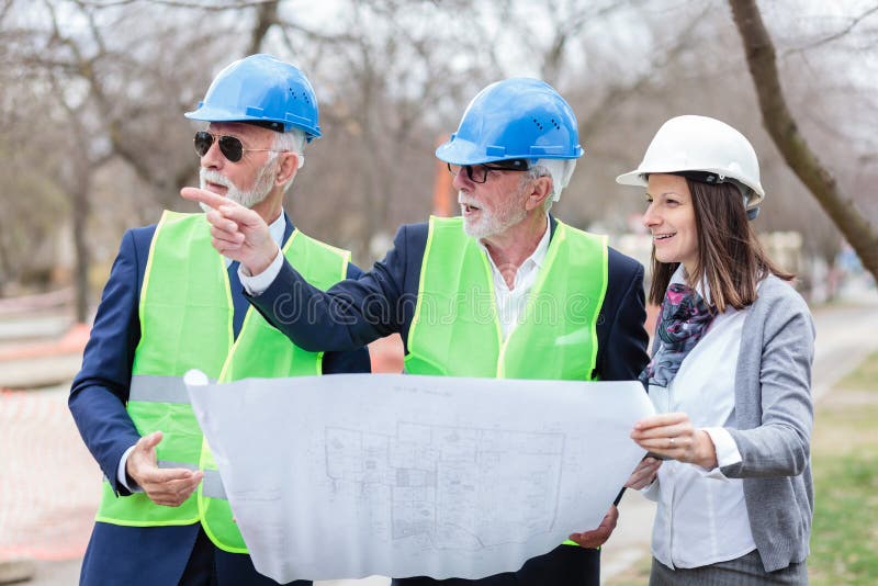 Grupo mezclado de arquitectos y de socios comerciales que discuten los detalles del proyecto durante la inspección de un emplazam fotos de archivo libres de regalías Grupo mezclado de arquitectos y de socios comerciales que discuten los detalles del proyecto durante la inspección de un emplazam fotos de archivo libres de regalías