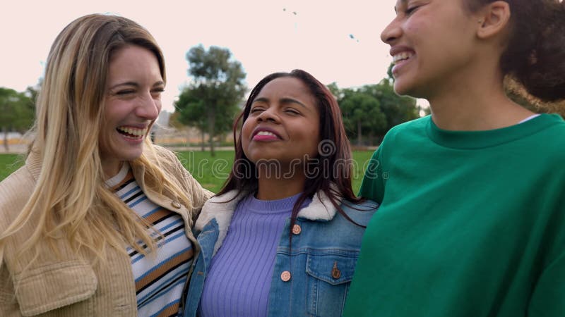 Grupo milenario de amigas multiétnicas riendo juntas al aire libre