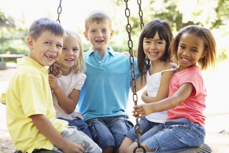 Grupp av barn som har gyckel i lekplats tillsammans