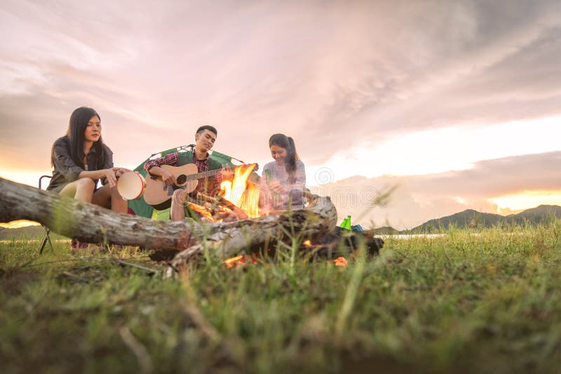 Grupp av handelsresande som campar och g? r picknicken och tillsammans spelar musik Berg- och sj? bakgrund Folk och livsstil royaltyfria bilder