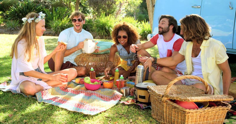 Grupp av hipstervänner som skrattar och har en picknick