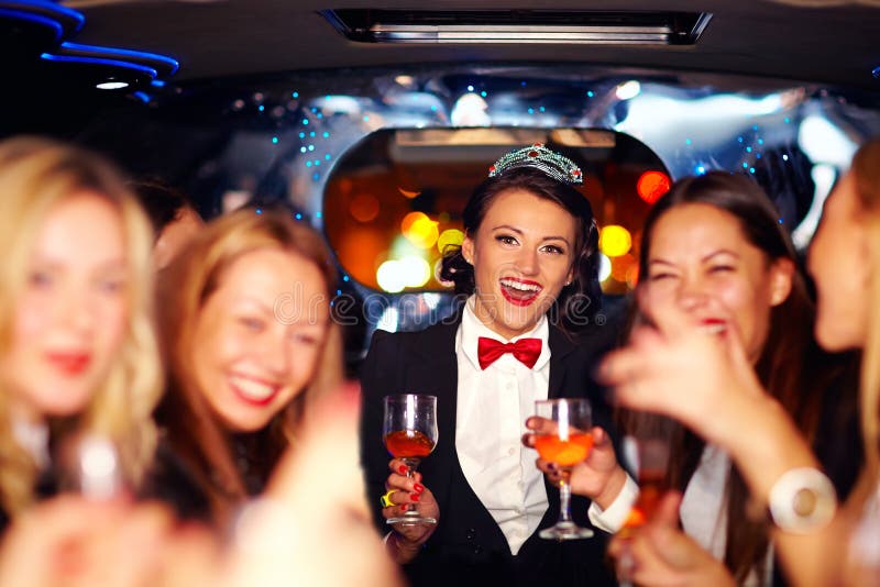 Grupp av lyckliga eleganta kvinnor som klirrar exponeringsglas i limousineet, möhippa royaltyfria foton