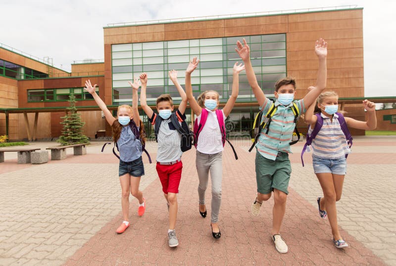 Grupp av lyckliga studenter i masker som lämnar skolan arkivbild