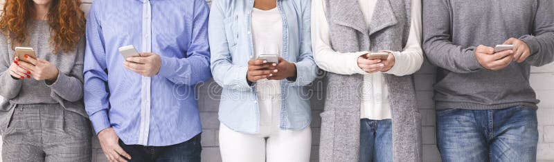 Grupp av millennials genom att använda mobiltelefoner som står i rad arkivfoto Grupp av millennials genom att använda mobiltelefoner som står i rad arkivfoto
