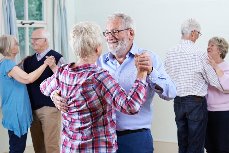 Grupp av pensionärer som tycker om som tillsammans dansar klubban arkivbild Grupp av pensionärer som tycker om som tillsammans dansar klubban arkivbild