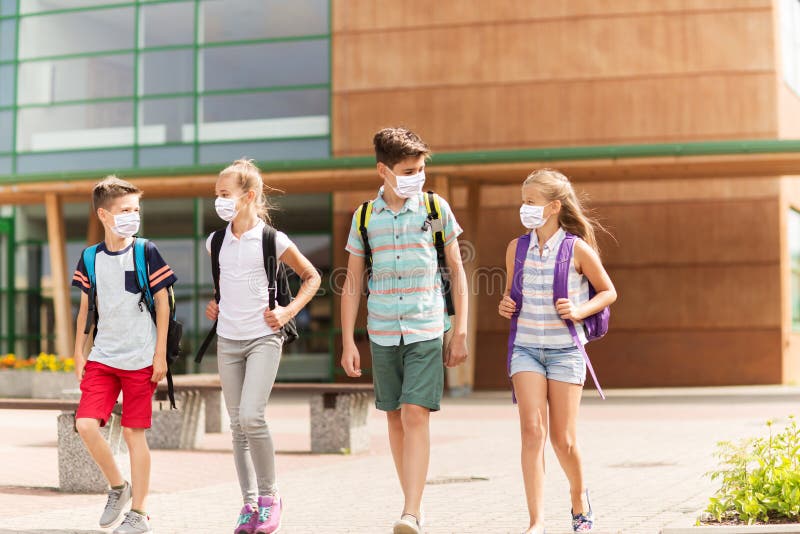 Grupp av skolelever i masker som lämnar skolan royaltyfri foto