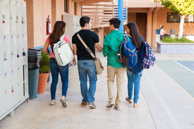 Back view of a group of high school students walking down the hallway and talking. Back view of a group of high school students walking down the hallway and talking