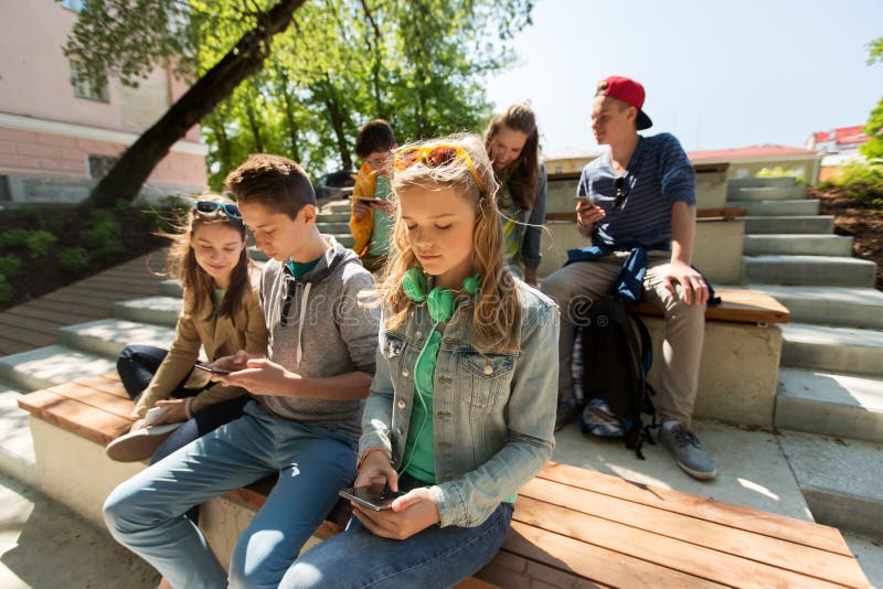 Grupp av tonårs- vänner med smartphones utomhus royaltyfri bild Grupp av tonårs- vänner med smartphones utomhus royaltyfri bild