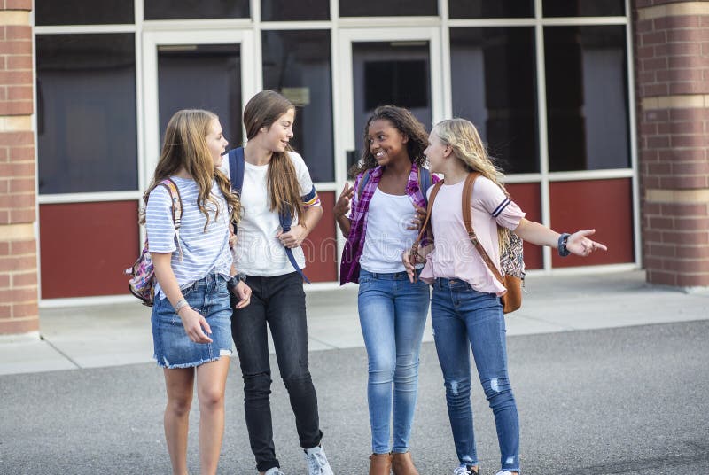 Grupp av tonårsflickor som skrattar och pratar tillsammans i skolan