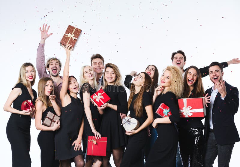 Grupp av ungt härligt folk i stilfull kläder med gåvaaskar i händer som har gyckel royaltyfri foto Grupp av ungt härligt folk i stilfull kläder med gåvaaskar i händer som har gyckel royaltyfri foto