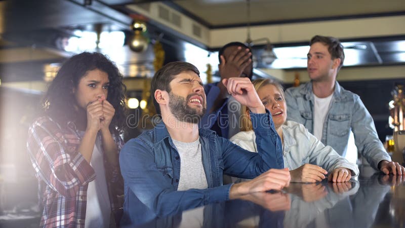 Grupp av v?nner som h?ller ?gonen p? sportprogrammet i st?ng, rubbning om den f?rlorande leken, nederlag royaltyfri fotografi Grupp av v?nner som h?ller ?gonen p? sportprogrammet i st?ng, rubbning om den f?rlorande leken, nederlag royaltyfri fotografi