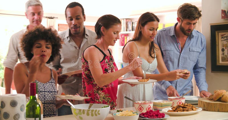 Grupp av vänner som hemma väljer mat från partibuffé