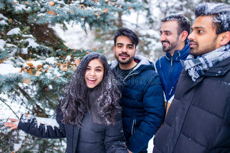 Grupp med fyra indianer som har kul att leka i snö utomhus och tillbringa helgdagar royaltyfri foto