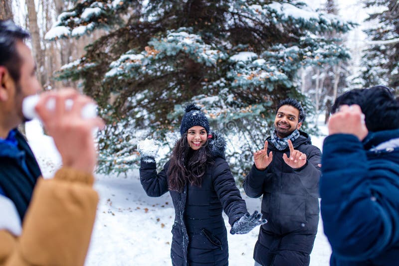 Grupp med fyra indianer som har kul att leka i snö utomhus och tillbringa helgdagar fotografering för bildbyråer
