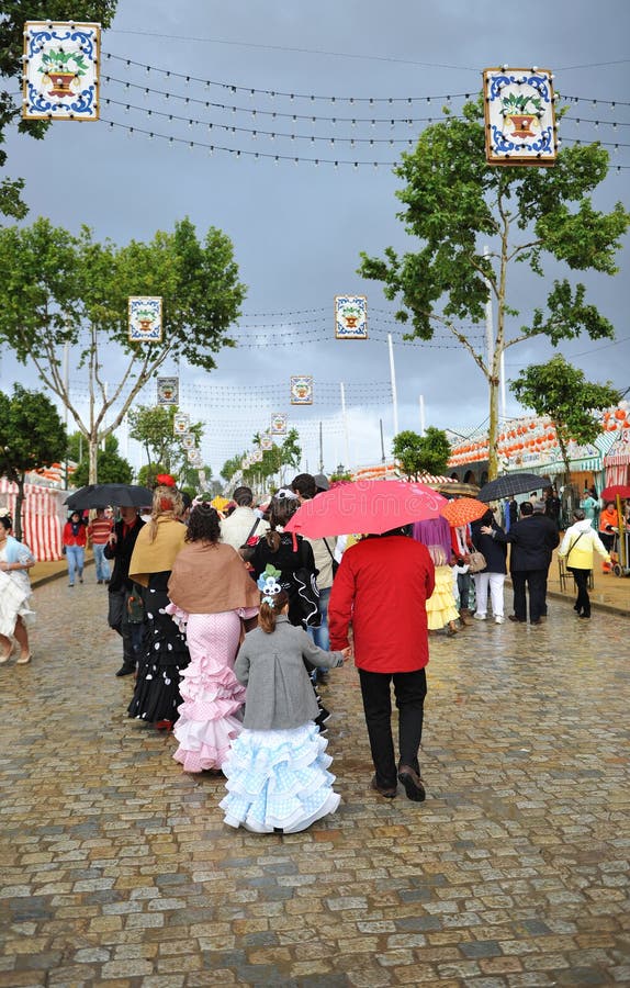Grupp människor under regnet, mässa i Seville, Andalusia, Spanien