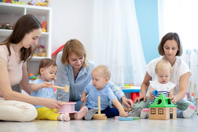 Gruppe der Säuglings- oder Kindergartenbetreuer Moms spielen mit Kindern in der Kinderkrippe