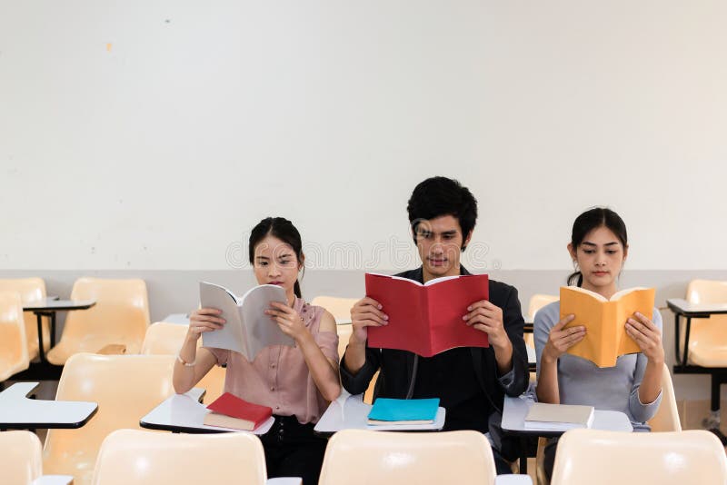 Gruppe des Buches mit drei Studenten Lesezusammen im Klassenzimmer stockbild Gruppe des Buches mit drei Studenten Lesezusammen im Klassenzimmer stockbild