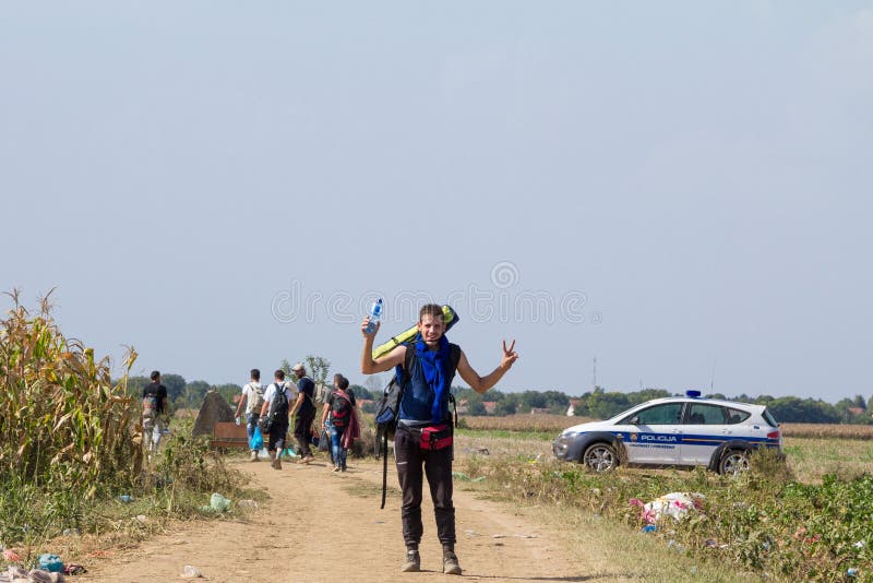 Gruppe Flüchtlinge, überschreiten vor einem kroatischen Polizeiwagen bei der Kreuzung von Grenze Serbiens Kroatien in Tovarnik SI lizenzfreie stockbilder Gruppe Flüchtlinge, überschreiten vor einem kroatischen Polizeiwagen bei der Kreuzung von Grenze Serbiens Kroatien in Tovarnik SI lizenzfreie stockbilder