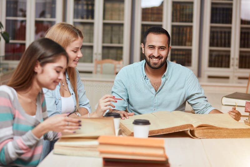 Gruppe gemischtrassige Leute, die mit Büchern in der Collegebibliothek studieren lizenzfreies stockfoto Gruppe gemischtrassige Leute, die mit Büchern in der Collegebibliothek studieren lizenzfreies stockfoto