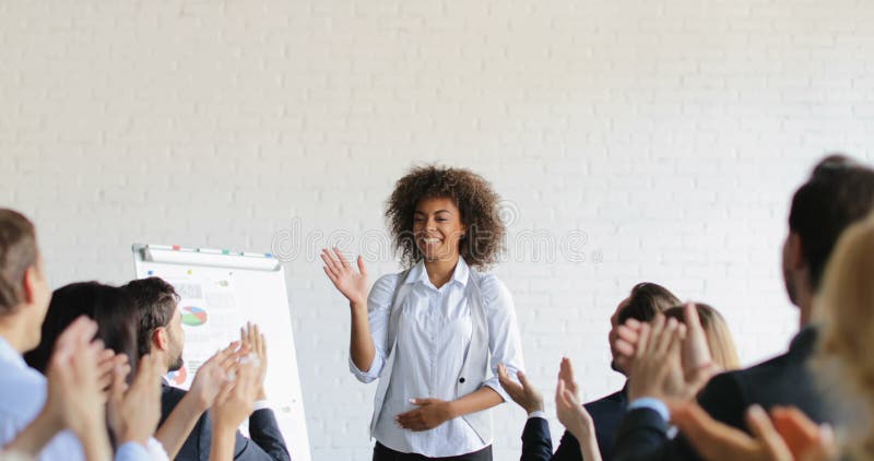 Gruppe Geschäftsleute, die glückliche Afroamerikaner-Geschäftsfrau With Successful Speech Congradulating während applaudieren