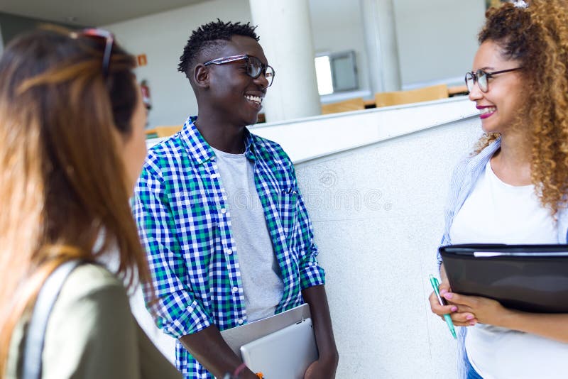 Gruppe glückliche junge Studenten, die in einer Universität sprechen lizenzfreie stockfotografie Gruppe glückliche junge Studenten, die in einer Universität sprechen lizenzfreie stockfotografie