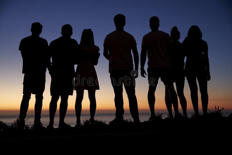 Gruppe junge Erwachsenen, die Sonnenuntergang durch das Meer bewundern