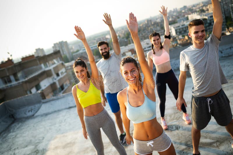 Gruppe junge Freunde der gl?cklichen Menschen, die drau?en bei Sonnenuntergang trainieren lizenzfreies stockfoto Gruppe junge Freunde der gl?cklichen Menschen, die drau?en bei Sonnenuntergang trainieren lizenzfreies stockfoto
