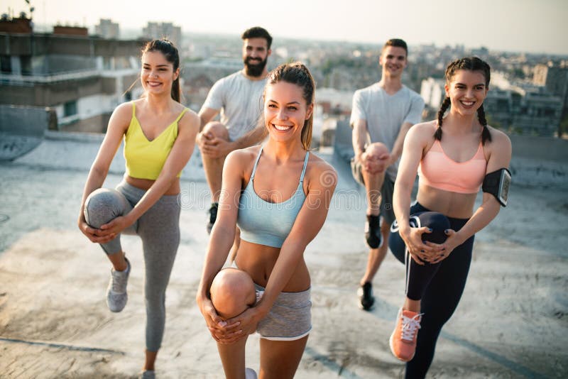 Gruppe junge Freunde der glücklichen Menschen, die draußen bei Sonnenuntergang trainieren stockbild Gruppe junge Freunde der glücklichen Menschen, die draußen bei Sonnenuntergang trainieren stockbild