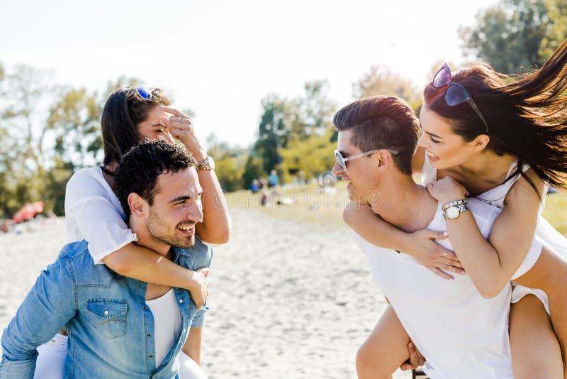 Gruppe junge glücklichen Menschen, die Frauen auf einem sandigen Strand tragen stockbilder Gruppe junge glücklichen Menschen, die Frauen auf einem sandigen Strand tragen stockbilder