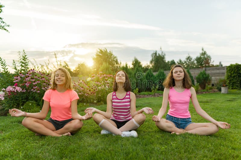 Gruppe junge Jugendlichen üben Yoga, meditieren, sitzen in einem Lotussitz auf dem Gras nahe dem Haus stockfoto Gruppe junge Jugendlichen üben Yoga, meditieren, sitzen in einem Lotussitz auf dem Gras nahe dem Haus stockfoto