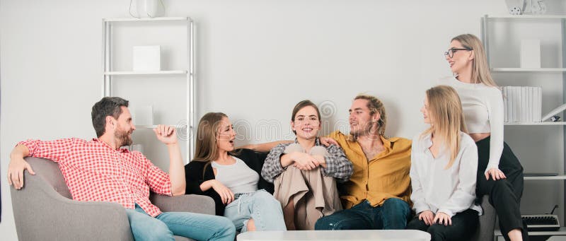 Gruppe junger Menschen, die auf Sofa sitzen und zu Hause sprechen. junge Freunde, die sich im Wohnzimmer gut amüsieren. stockbild