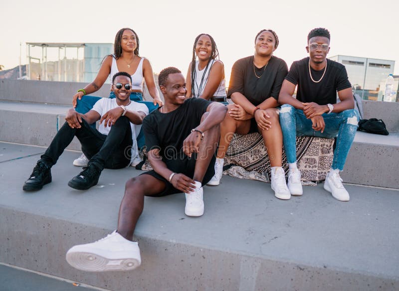 Gruppe junger moderne Afrikanerschwarzfreunde, die Glück zusammen sitzen lizenzfreie stockbilder