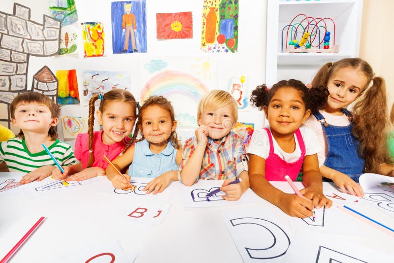 Group of diverse looking boys and girls in kindergarten class drawing letters in early reading class. Group of diverse looking boys and girls in kindergarten class drawing letters in early reading class