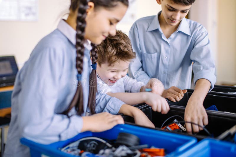 Group of happy kids of different age choose parts of robotic electric toys for building robots at robotics school lesson. Group of happy kids of different age choose parts of robotic electric toys for building robots at robotics school lesson.