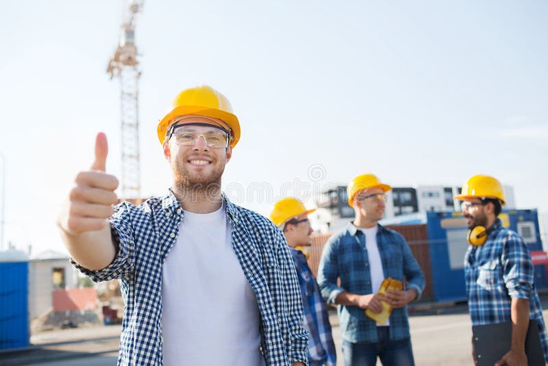 Gruppe lächelnde Erbauer in den Hardhats draußen stockfotografie Gruppe lächelnde Erbauer in den Hardhats draußen stockfotografie
