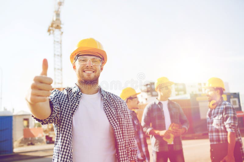 Gruppe lächelnde Erbauer in den Hardhats draußen stockfotografie Gruppe lächelnde Erbauer in den Hardhats draußen stockfotografie